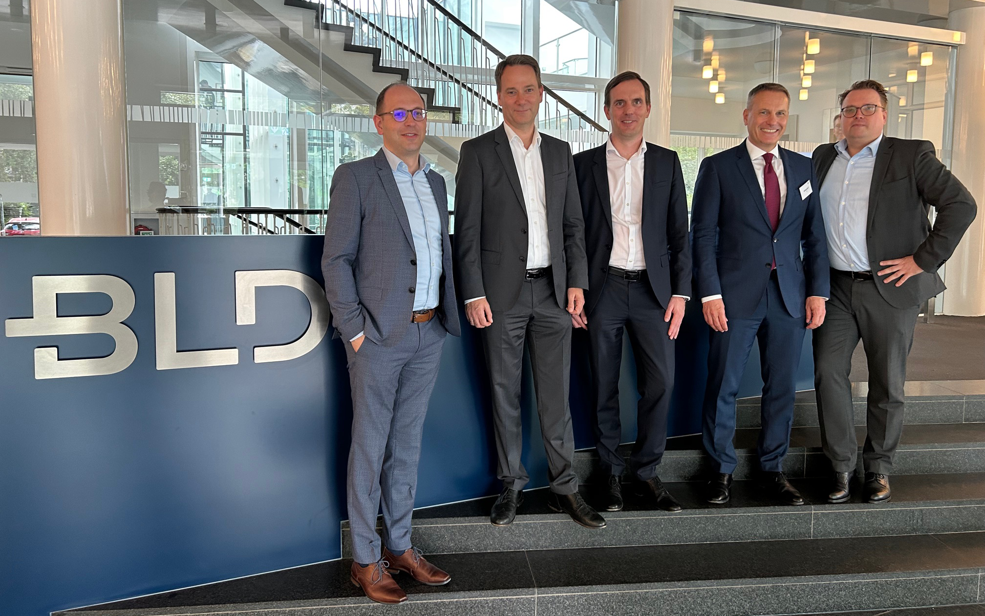 Auf dem Gruppenfoto sind fünf Personen drauf, sie stehen im Eingangsbereich des kölner Standorts.