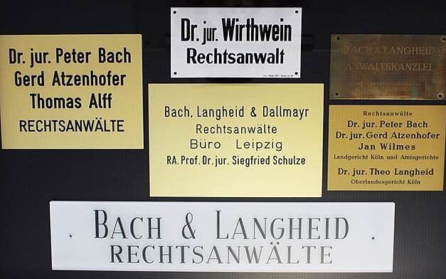 Auf dem Bild sieht man sechs Namensschilder auf den Türschilder. Es sind zweimal von Dr. jur. Perter Bach, einmal von Dr. jur. Wirthwein und dreimal von Bach und Langheid.